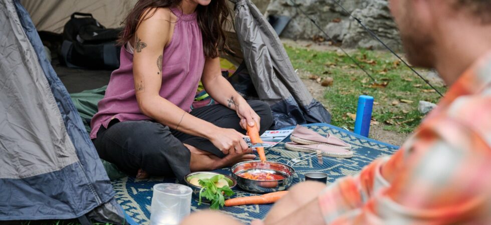 Frau kocht beim Camping