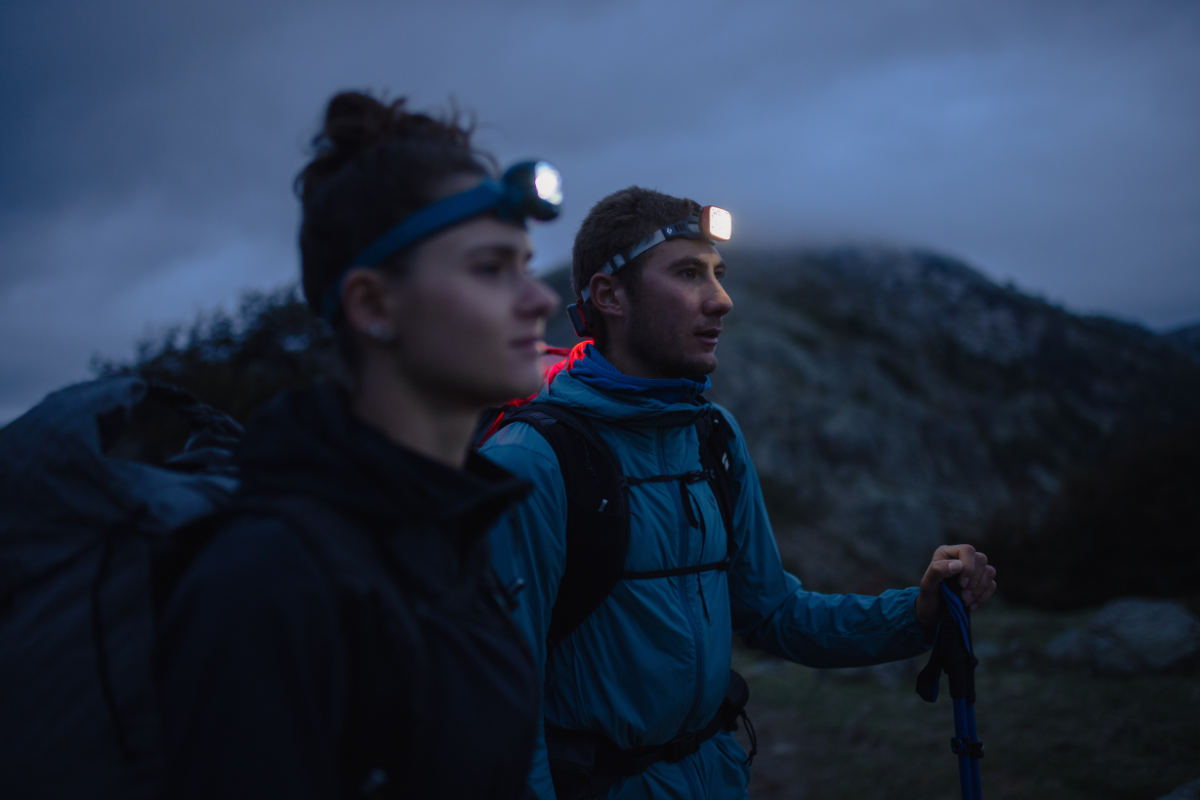 2 Wanderer mit Stirnlampen in Dämmerung am Berg.