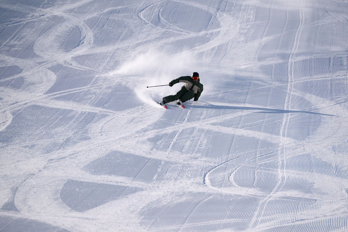 Skifahrer fährt auf frisch gewalzter Piste Carvingschwünge