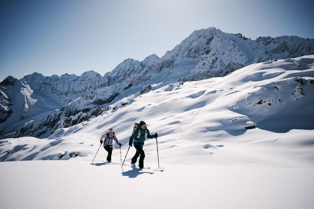 Zwei Tourengeher im Aufstieg vor Bergkulisse