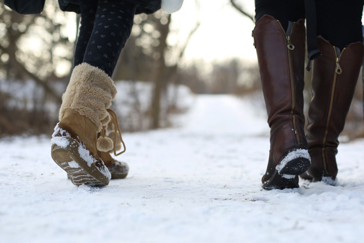 Zwei Personen laufen mit Winterstiefeln auf verschneitem Weg