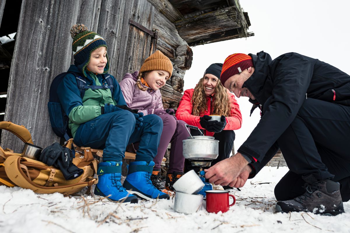 Kinder mit Eltern beim Kochen im Schnee
