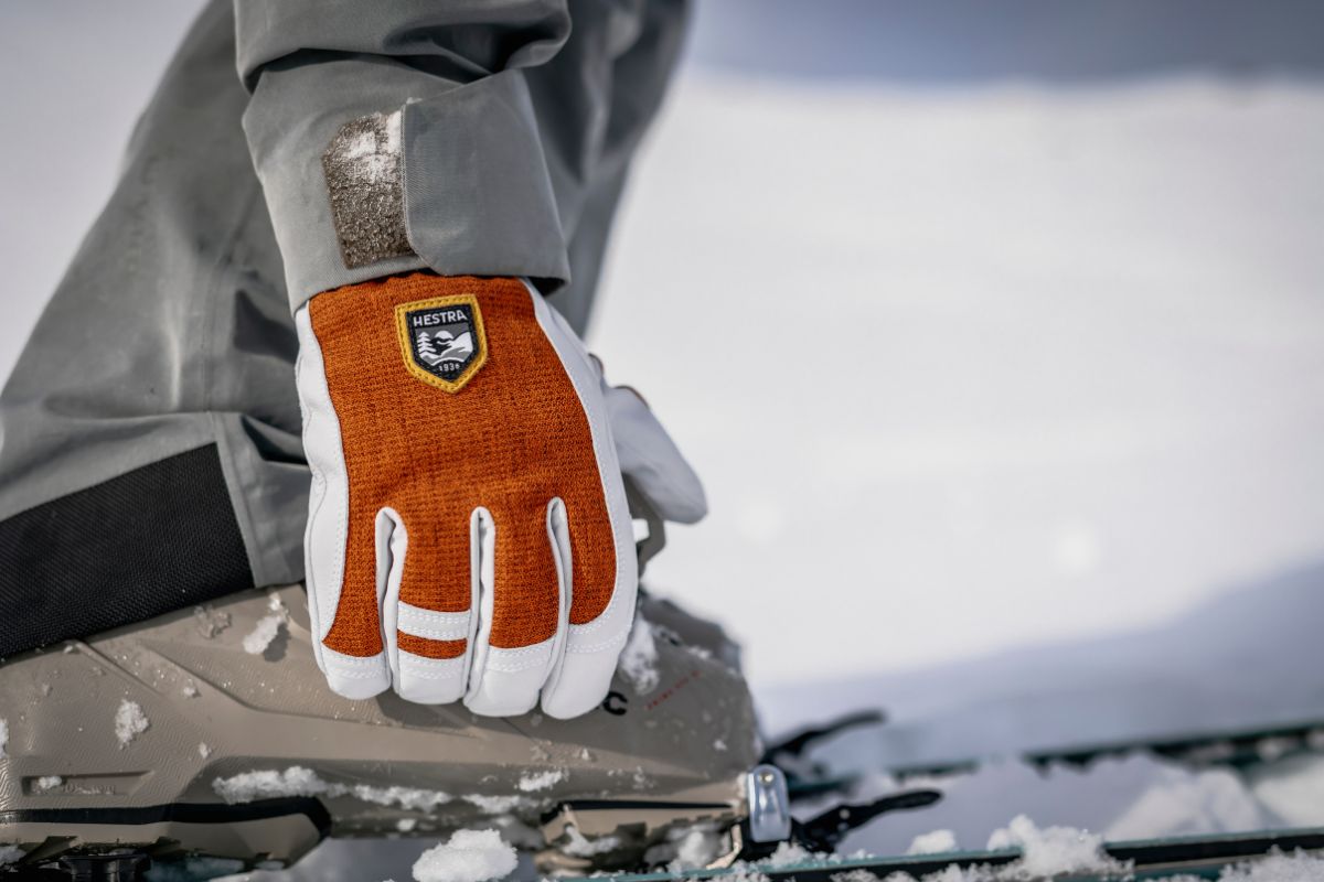 Skifahrer schließt Schnallen an Skischuh mit Handschuh