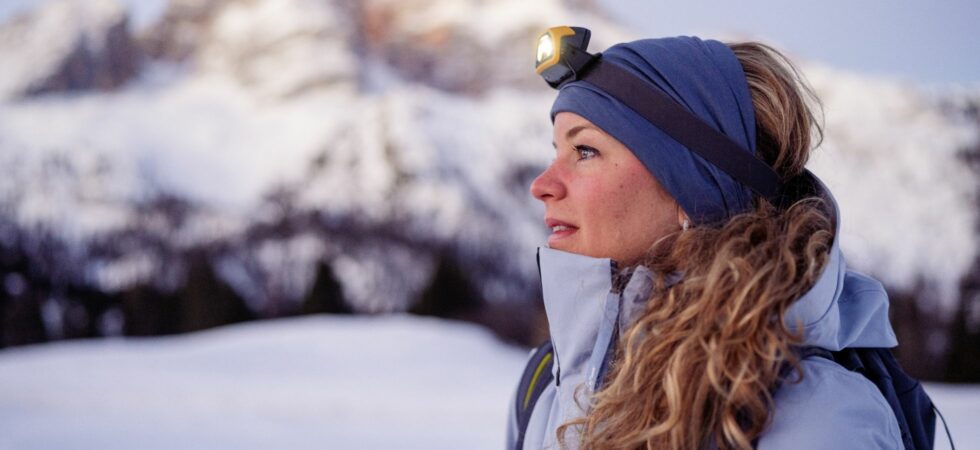 Frau mit Stirnlampe beim Winterwandern