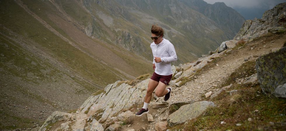 Ein Läufer ist beim Trailrunning auf einem felsigen Bergpfad unterwegs.