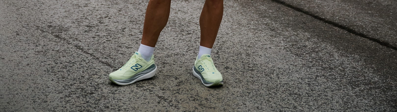 Helle Laufschuhe stehen auf einer strukturierten Straße.