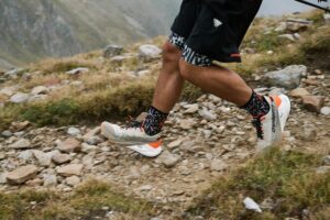 Trailrunning-Schuhe laufen über einen steinigen Bergweg.