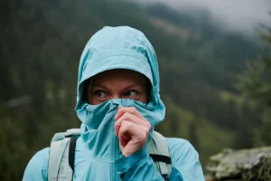 Wanderin schützt sich mit hochgezogener Kapuze vor Regen in den Bergen.