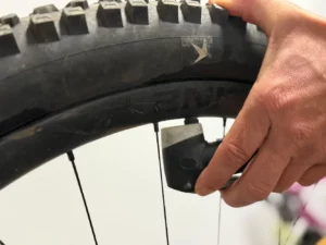 Eine Hand befestigt den Anschluss am Fahrradventil zur Kontrolle des Reifendrucks.
