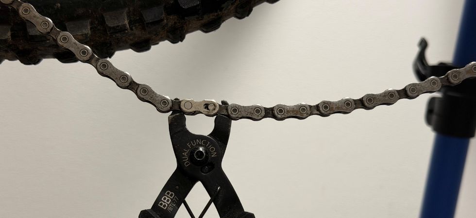 Eine Verschlussgliedzange öffnet ein Kettenschloss beim Fahrradkette wechseln.
