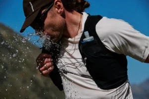 Ein Läufer trinkt während einer Gravel Running Tour aus einer Wasserflasche in der Laufweste.