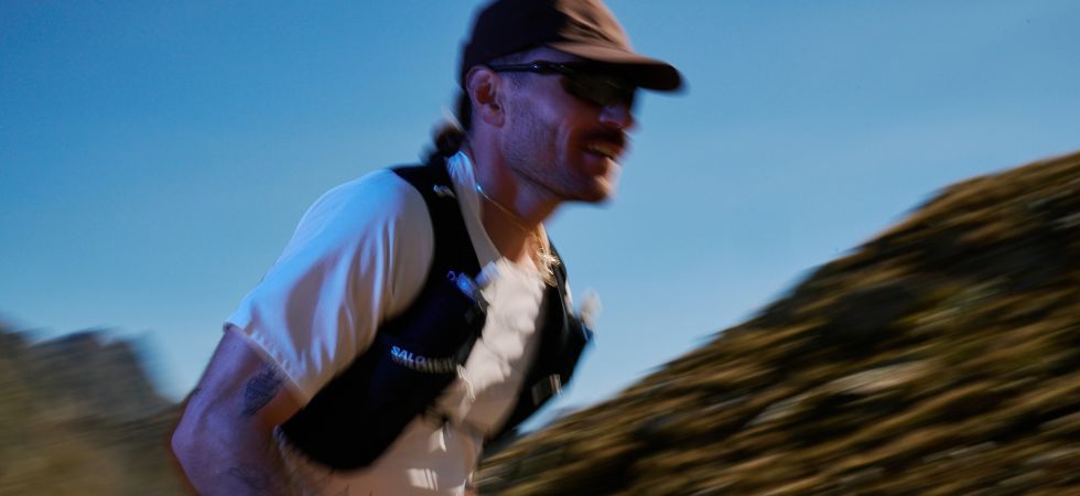 Läufer mit Trailrunning Ausrüstung läuft durch eine Berglandschaft.