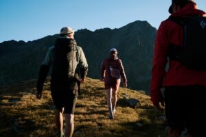 Hiking group walking along an alpine mountain trail in low sunlight.